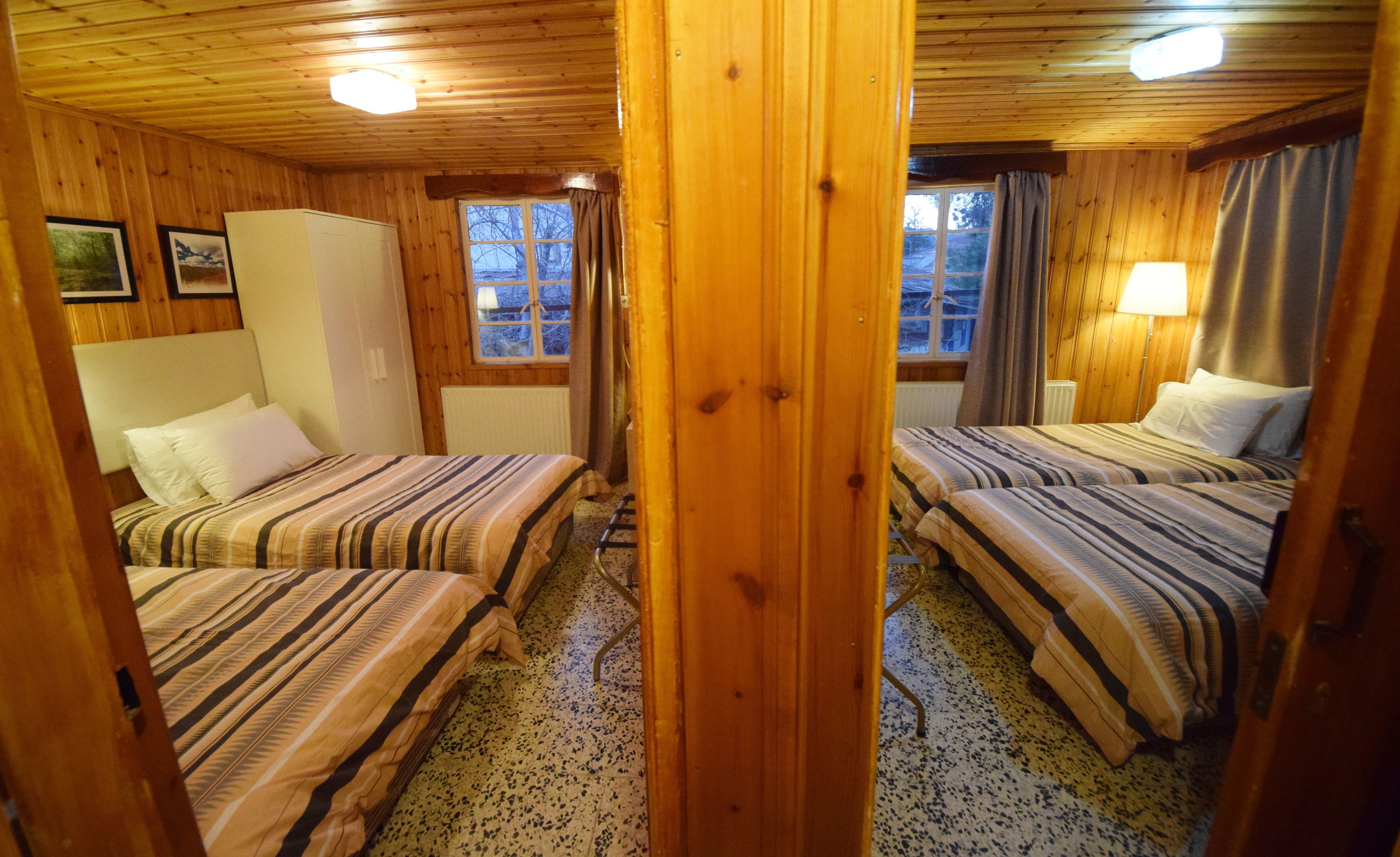 Uma cabana de madeira com duas camas, uma janela e um radiador.