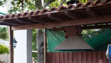 A stone wall with a tiled roof structure, a green tarp, and a potted plant.