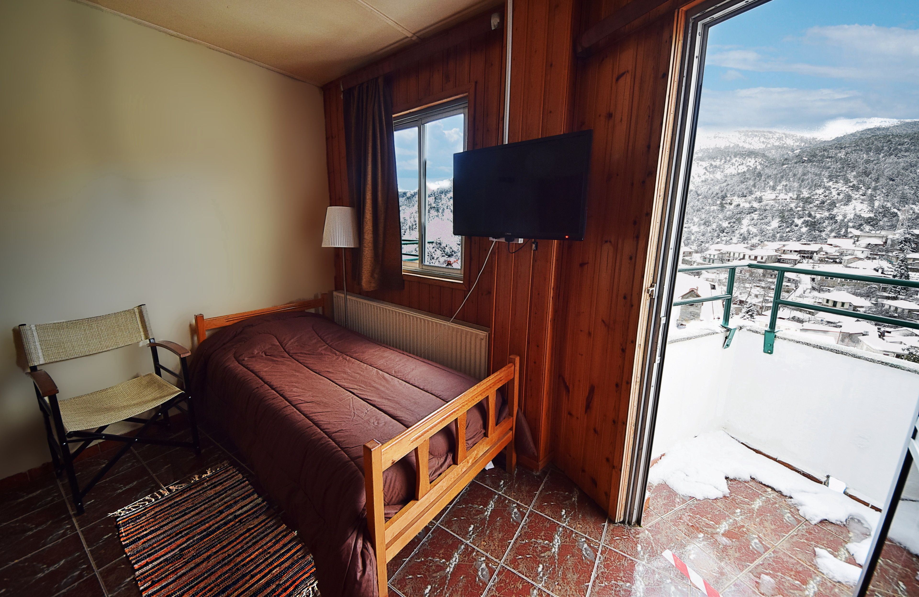 Una habitación con cama, una silla, un televisor y vistas a un paisaje nevado.
