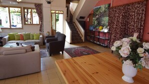 A spacious living area with a sofa, armchairs, a wooden coffee table, and a staircase leading to an upper level.