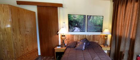 A bedroom with a wooden bed, two bedside lamps, a nightstand, and a wardrobe.