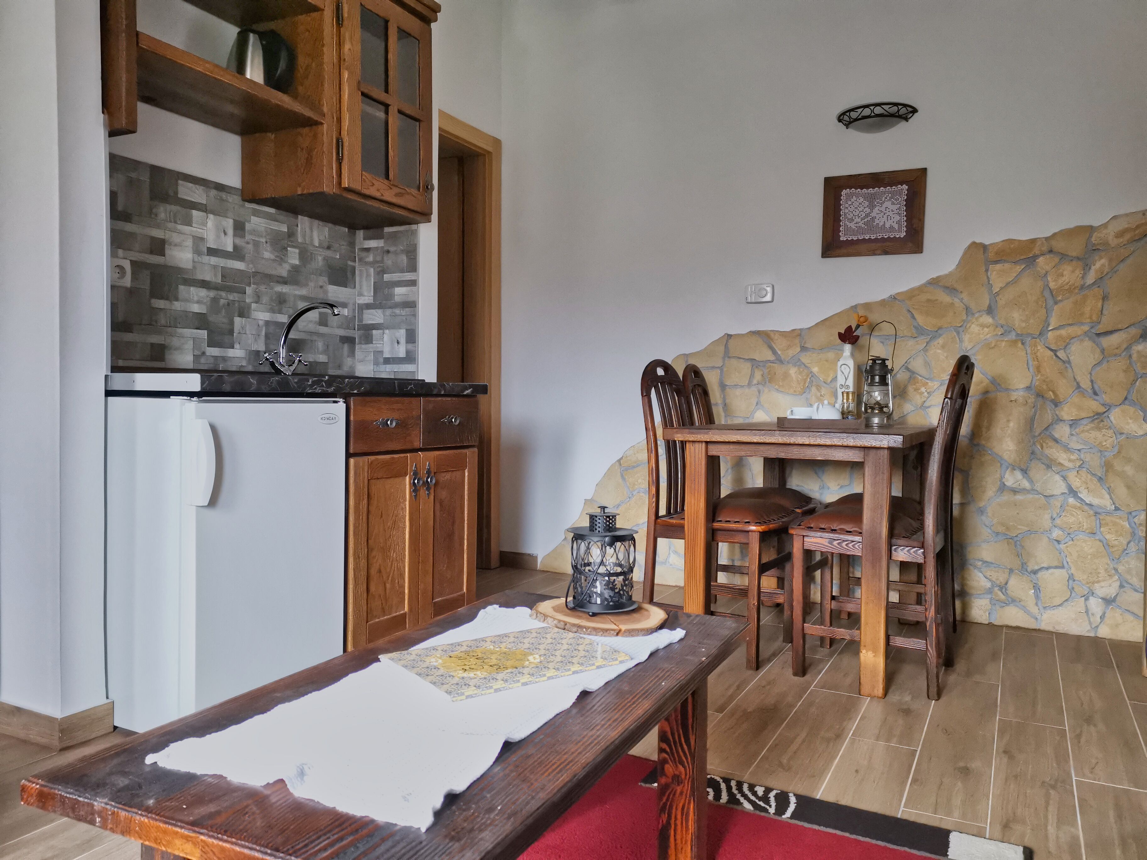 Una cocina compacta con armarios de madera, un refrigerador y una pared de piedra.