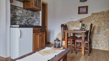 Una cocina compacta con armarios de madera, un refrigerador y una pared de piedra.