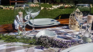 A picnic setup with a checkered tablecloth, wine glasses, plates, and a basket of lavender.