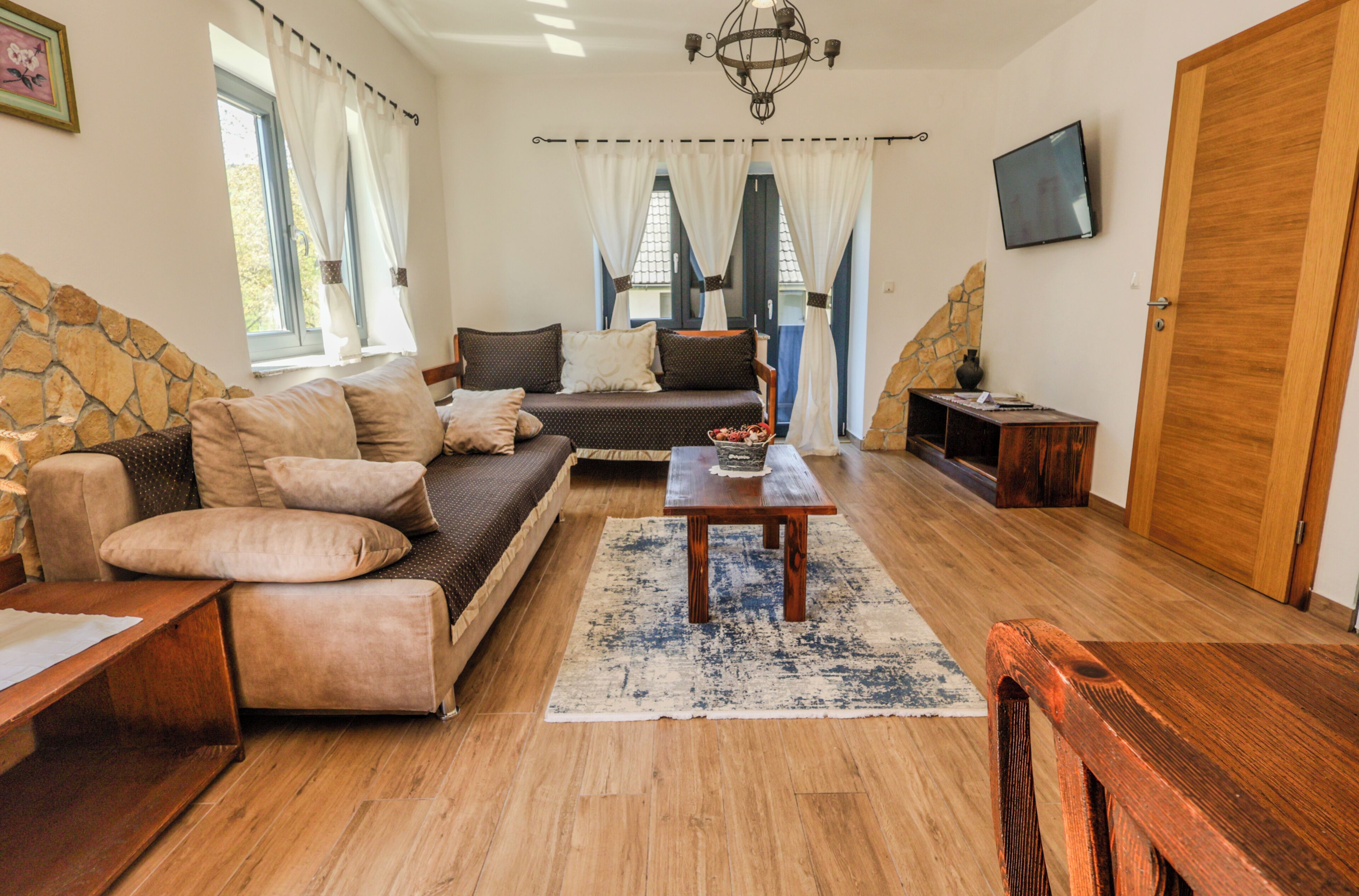 Una sala de estar acogedora con un sofá, una mesa de centro de madera y una pared de acento de piedra.