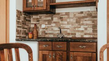 A kitchen with wooden cabinets, a herringbone tile backsplash, and a marble countertop.