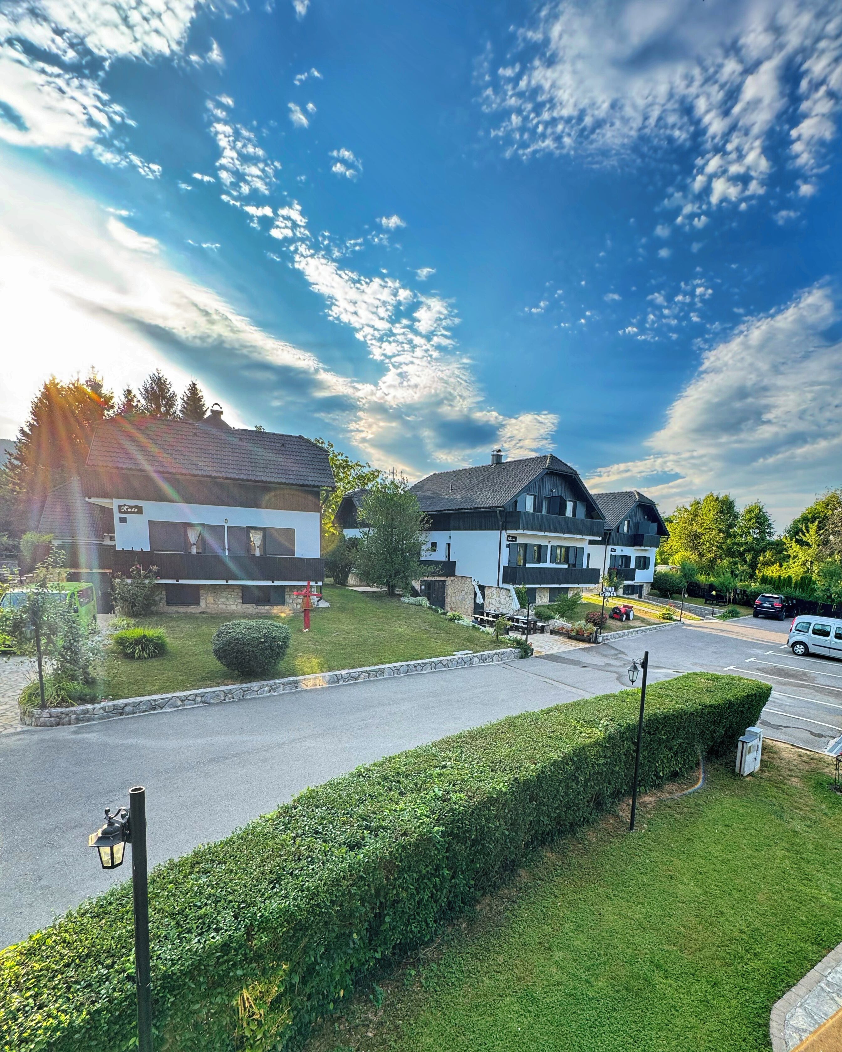 A residential street with houses, a well-maintained lawn, and a clear sky.