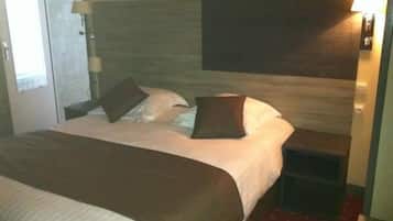 Una habitación de hotel con cama, mesita de noche y lámpara de pared.