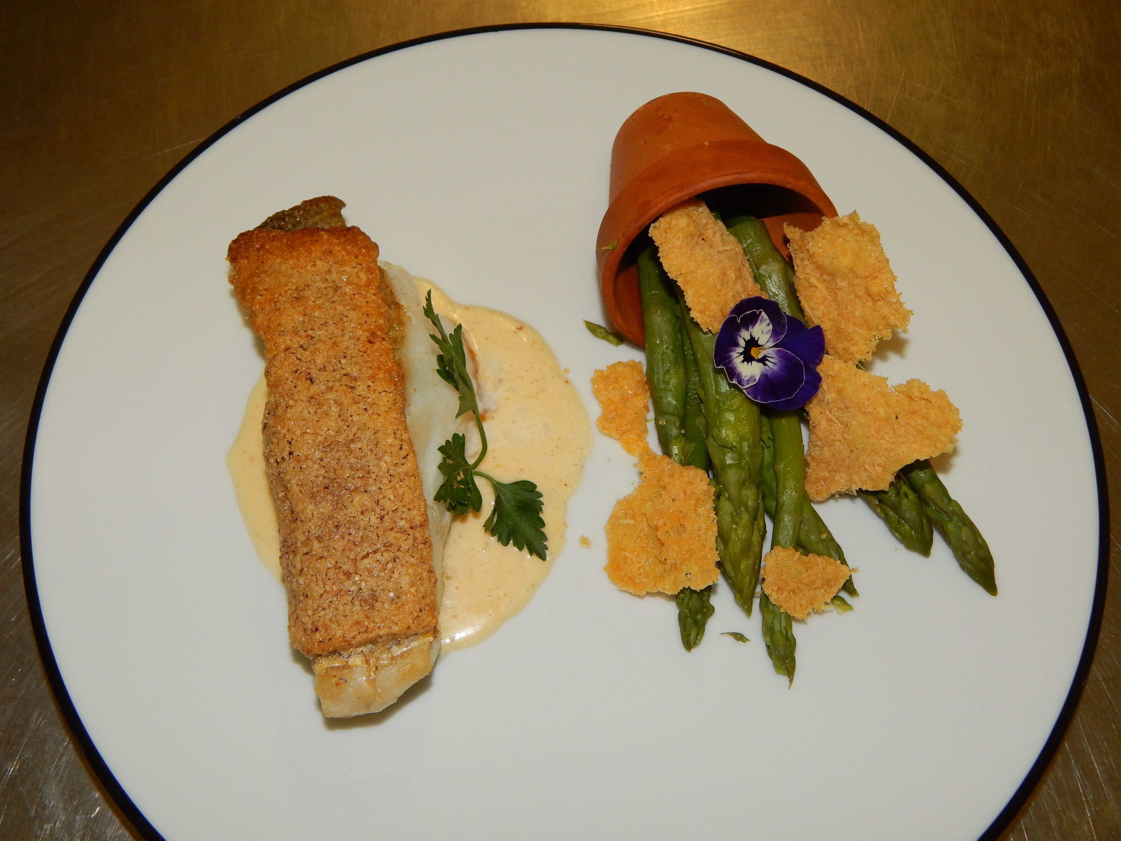 A plate with a rolled pastry, asparagus, and a small orange bowl.