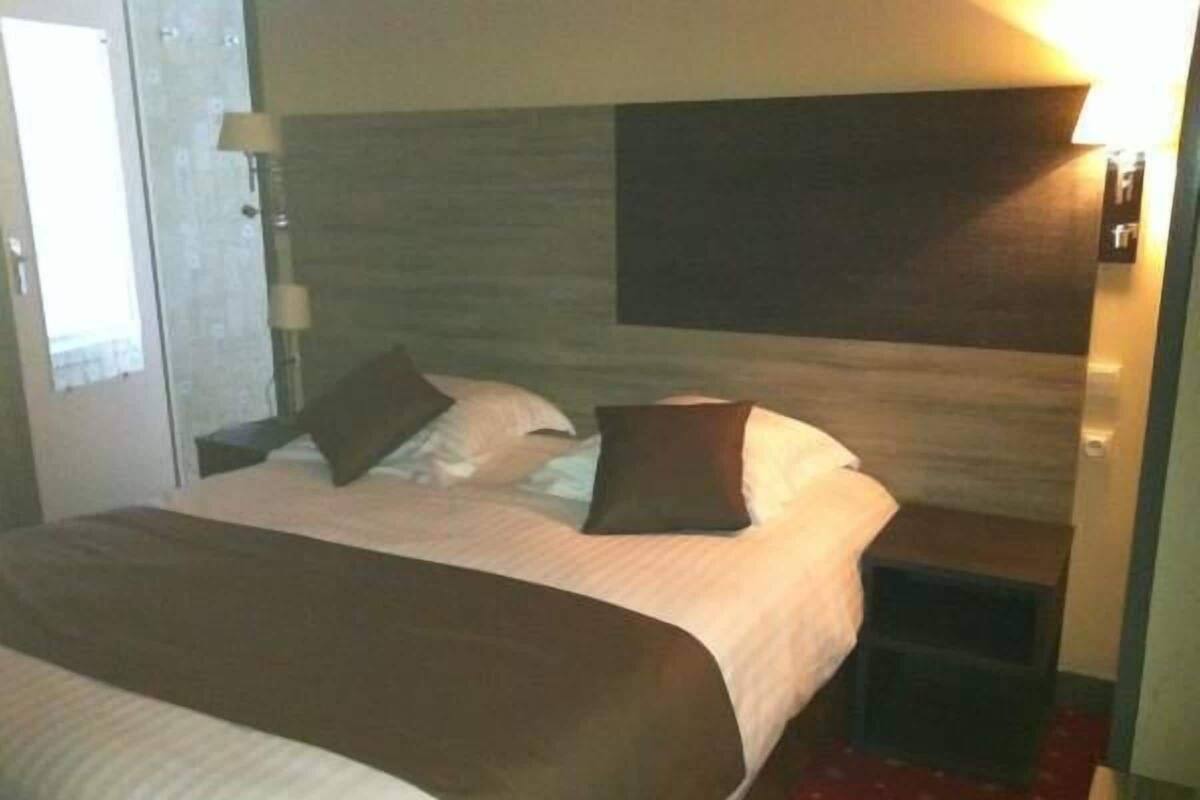 Habitació d'hotel amb un llit, una taula de nit, una làmpada i un llum de paret.