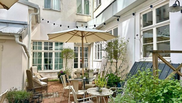 A patio with outdoor furniture, a table, and a large umbrella.