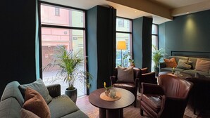 A modern living room with a sofa, chairs, a coffee table, and large windows.