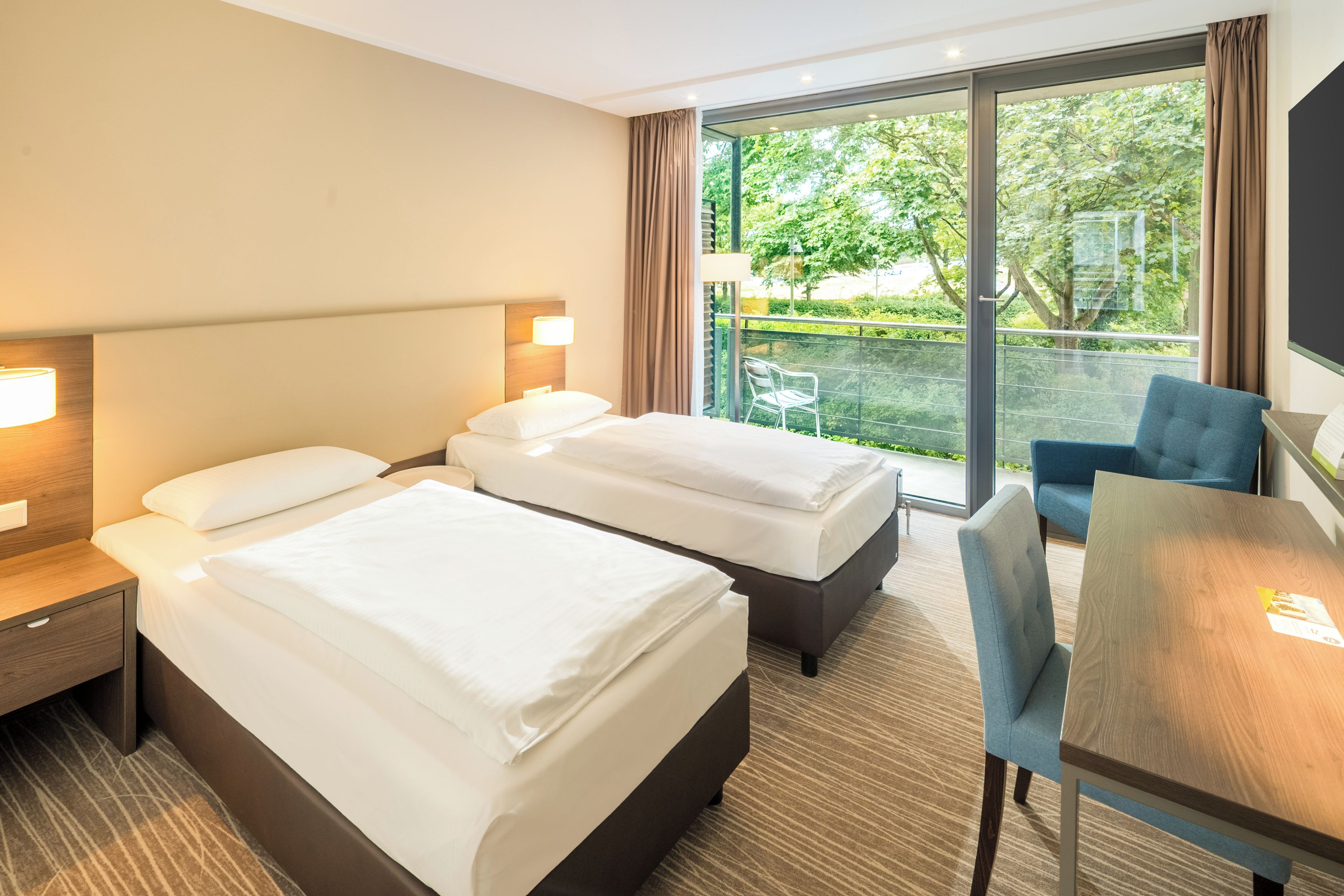 Quarto de hotel com duas camas, uma escrivaninha e uma cadeira.