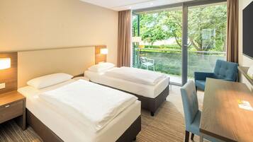 Quarto de hotel com duas camas, uma escrivaninha e uma cadeira.