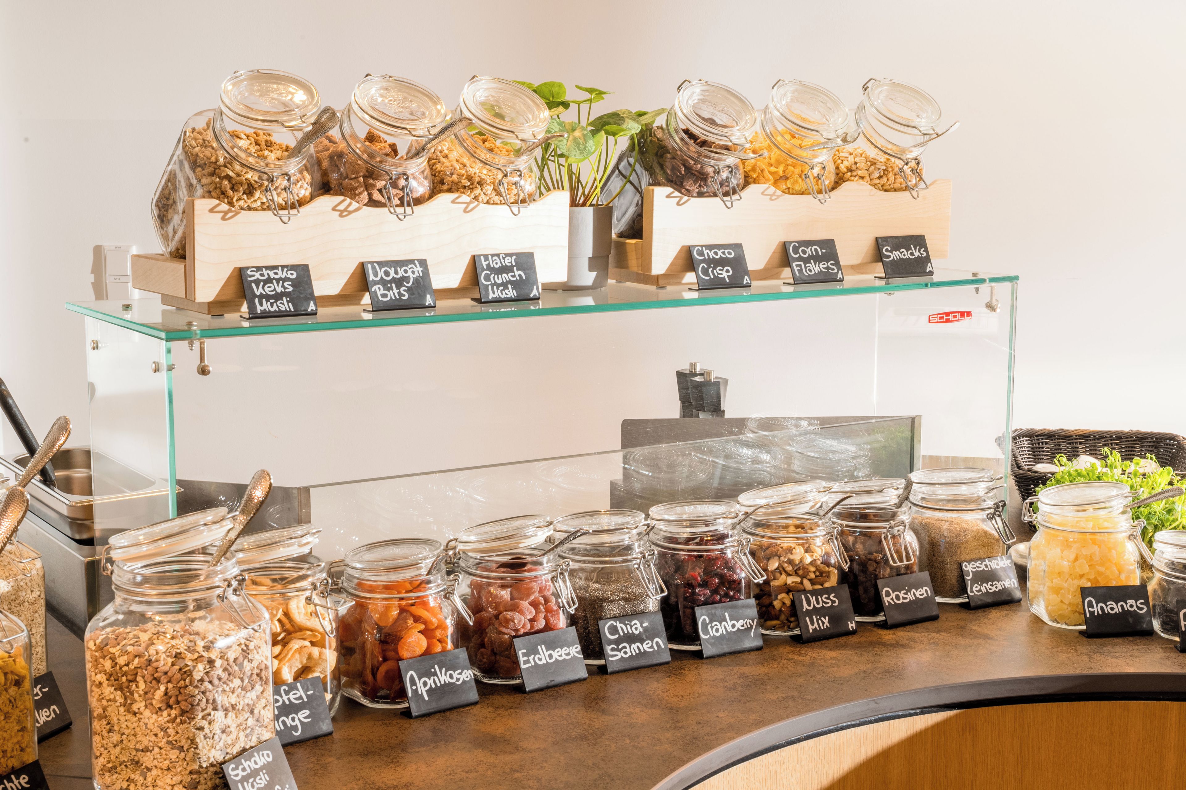 A food display with various jars labeled with names like 'Schoko Keks Müsli' and 'Dugout Bits'.