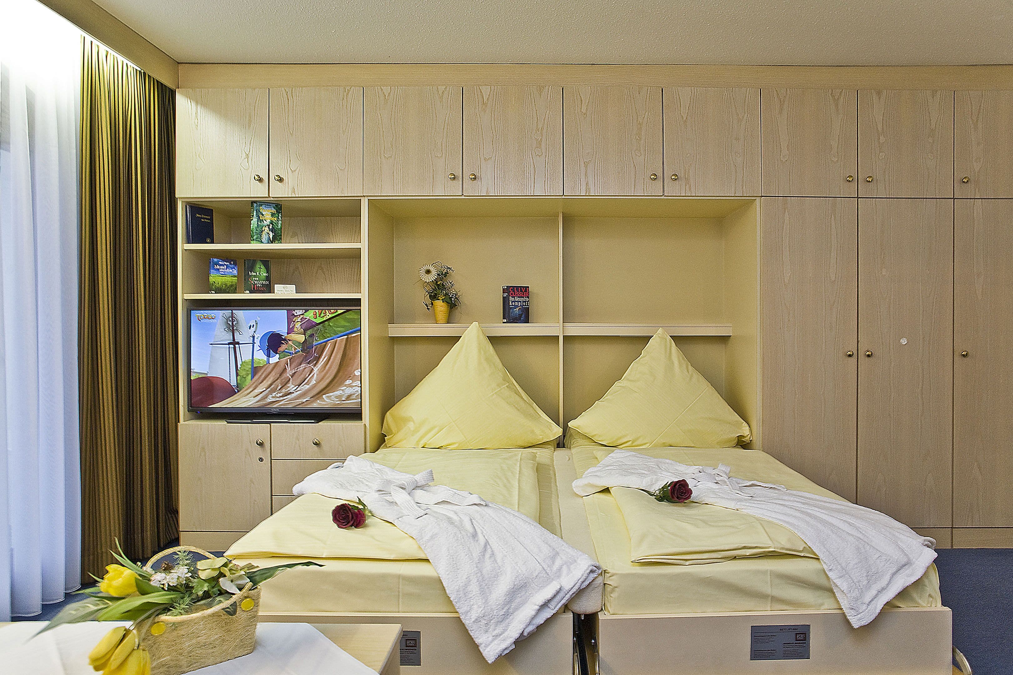 Une chambre d’hôtel avec deux lits, une télévision et une bibliothèque.