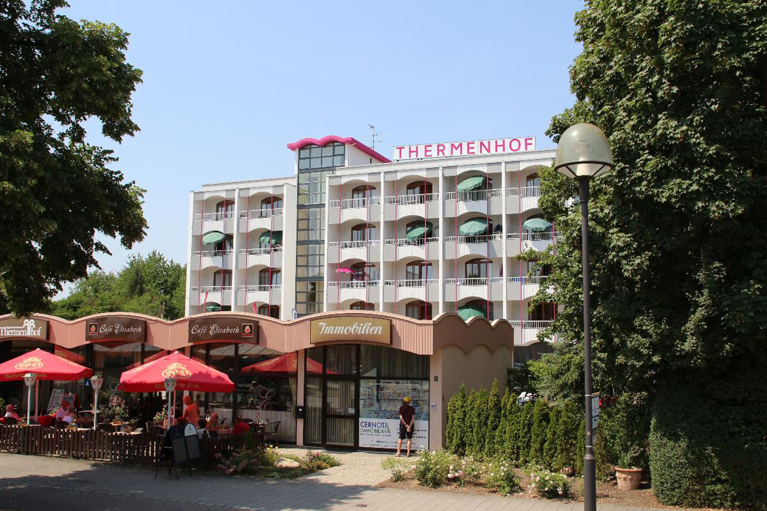 A hotel with multiple balconies, outdoor seating areas, and a sign for 'Café Elisabeth'.