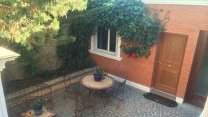 A patio with a round table and chairs, surrounded by a stone floor. - Hôtel Saint Alban (Saint-Maur-des-Fosses)