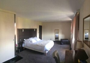 A hotel room with a bed, bedside table, chair, and a mirror on the wall. - Hôtel Saint Alban (Saint-Maur-des-Fosses)