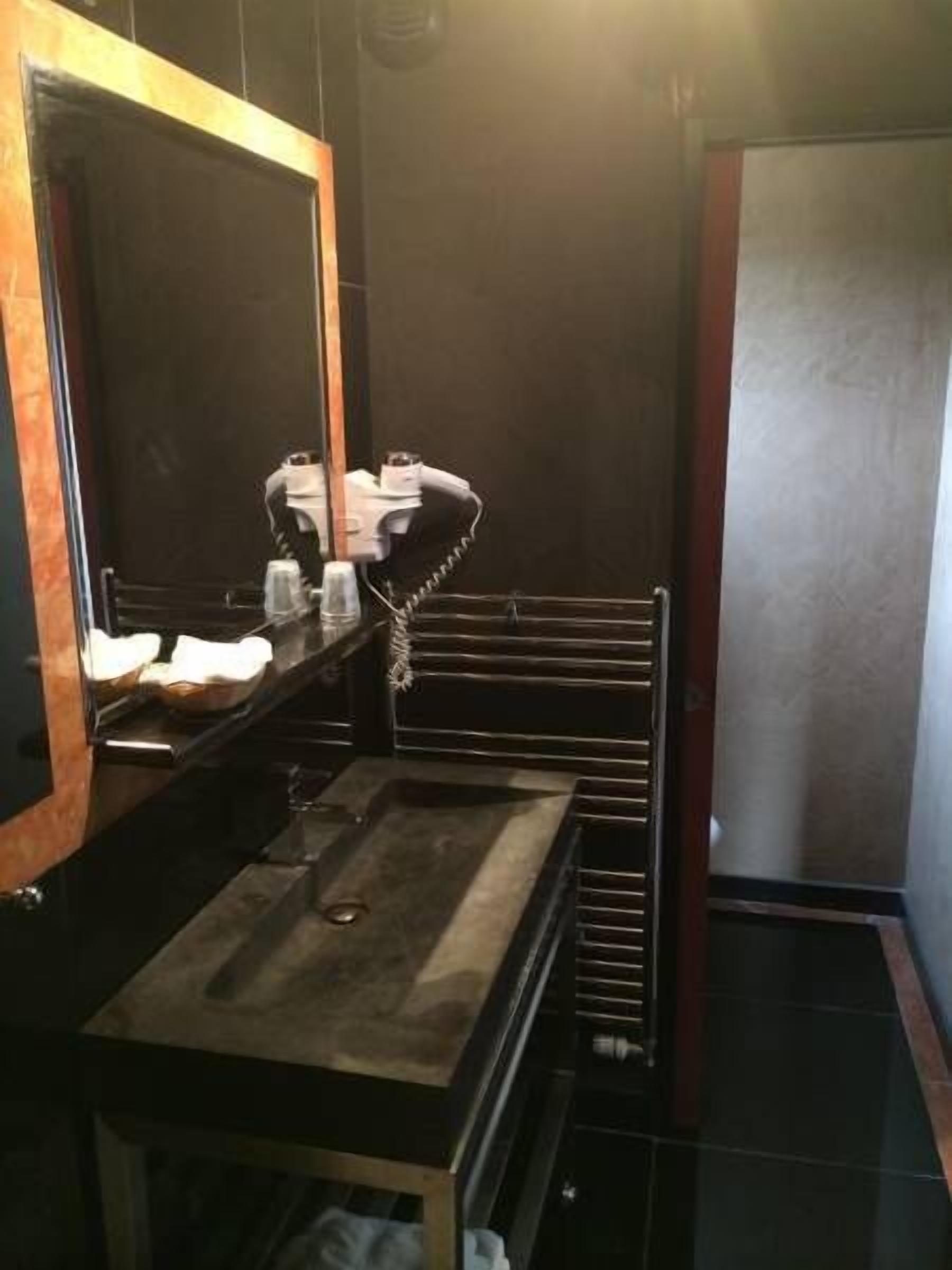 A bathroom with a large mirror, a sink, and a towel rack.