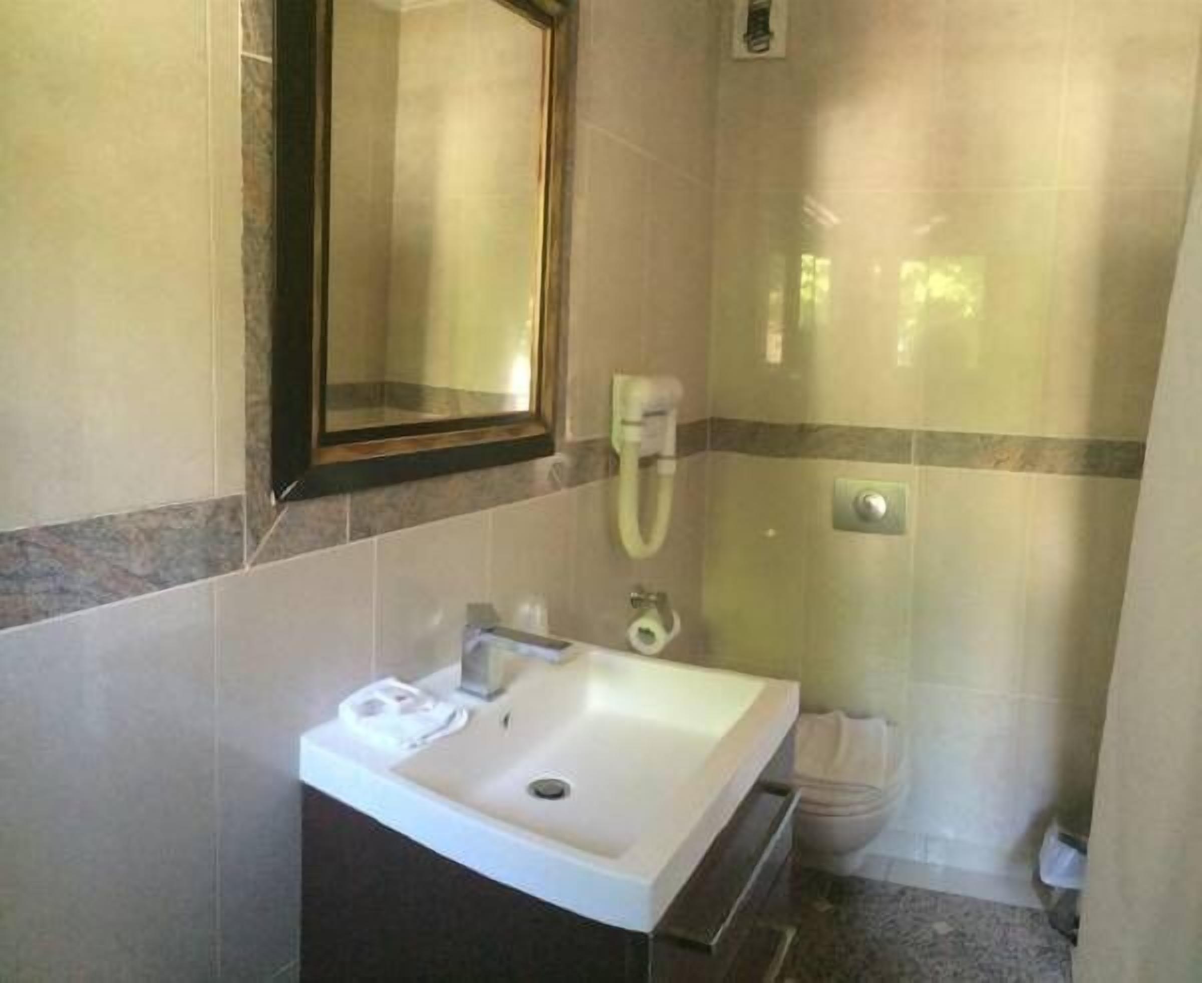 A bathroom with a sink, mirror, and shower area.