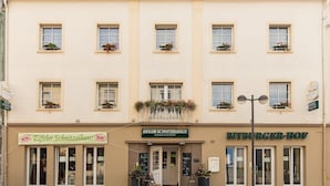 A building with multiple windows, a balcony with flowers, and signs for 'Eifeler Schnitztelhaus' and 'Bitburger-Hof'. - Hotel Bitburger Hof (Bitburg)