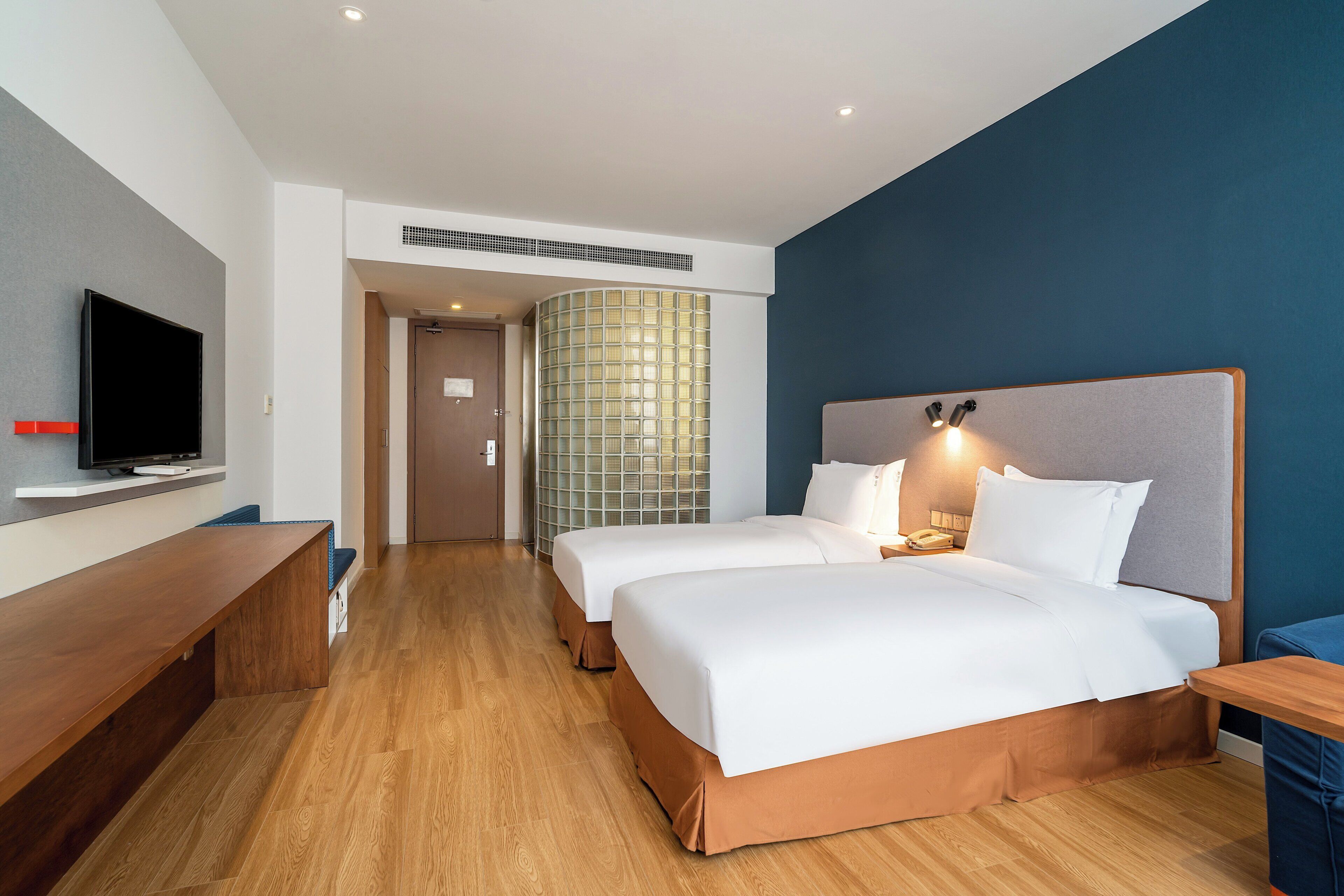 Une chambre d’hôtel équipée d’une télévision, de deux lits, d’un bureau et d’une salle de bain.