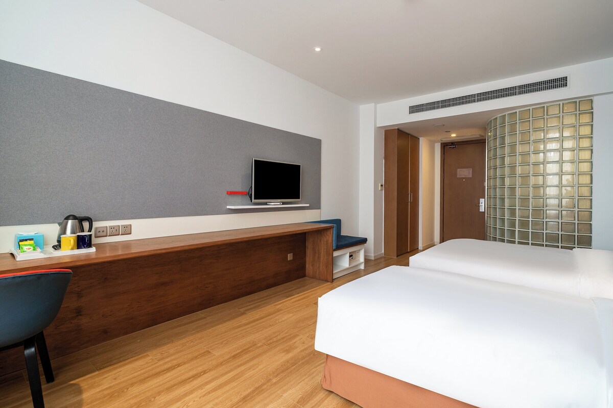 Quarto de hotel com uma mesa de madeira, televisão, cama e área de estar.