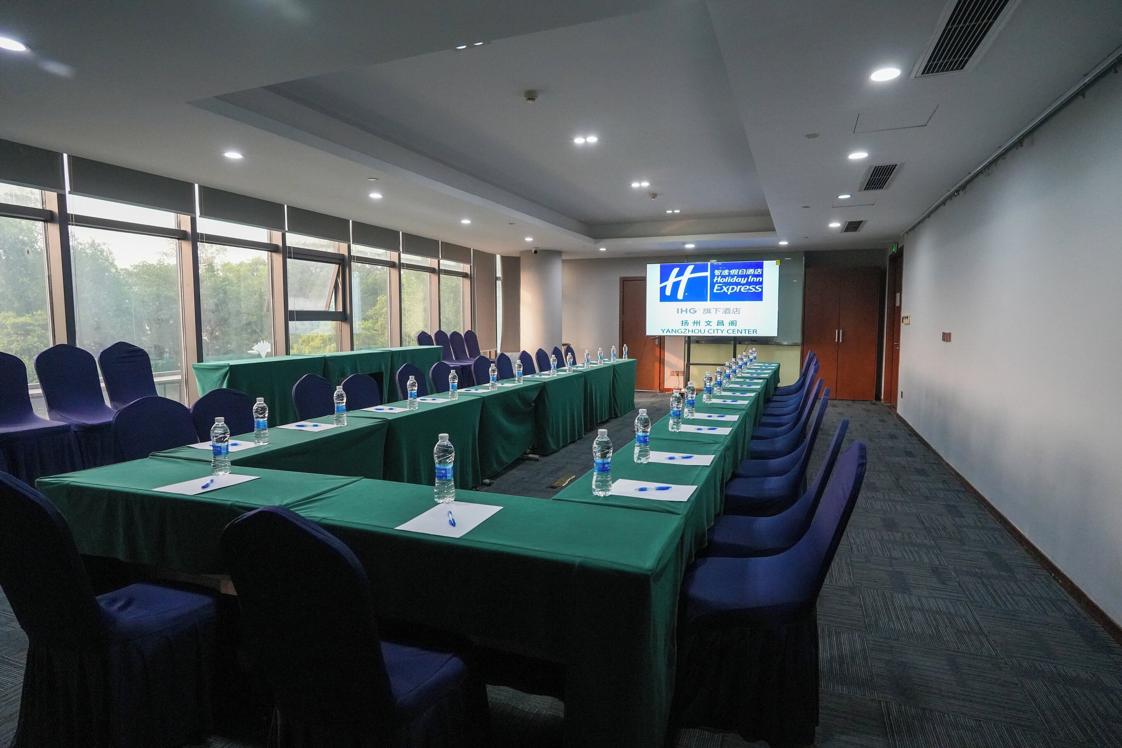 A conference room with a long table, chairs, and a projection screen.