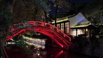 A traditional building with a red-lit bridge over a reflective water body.
