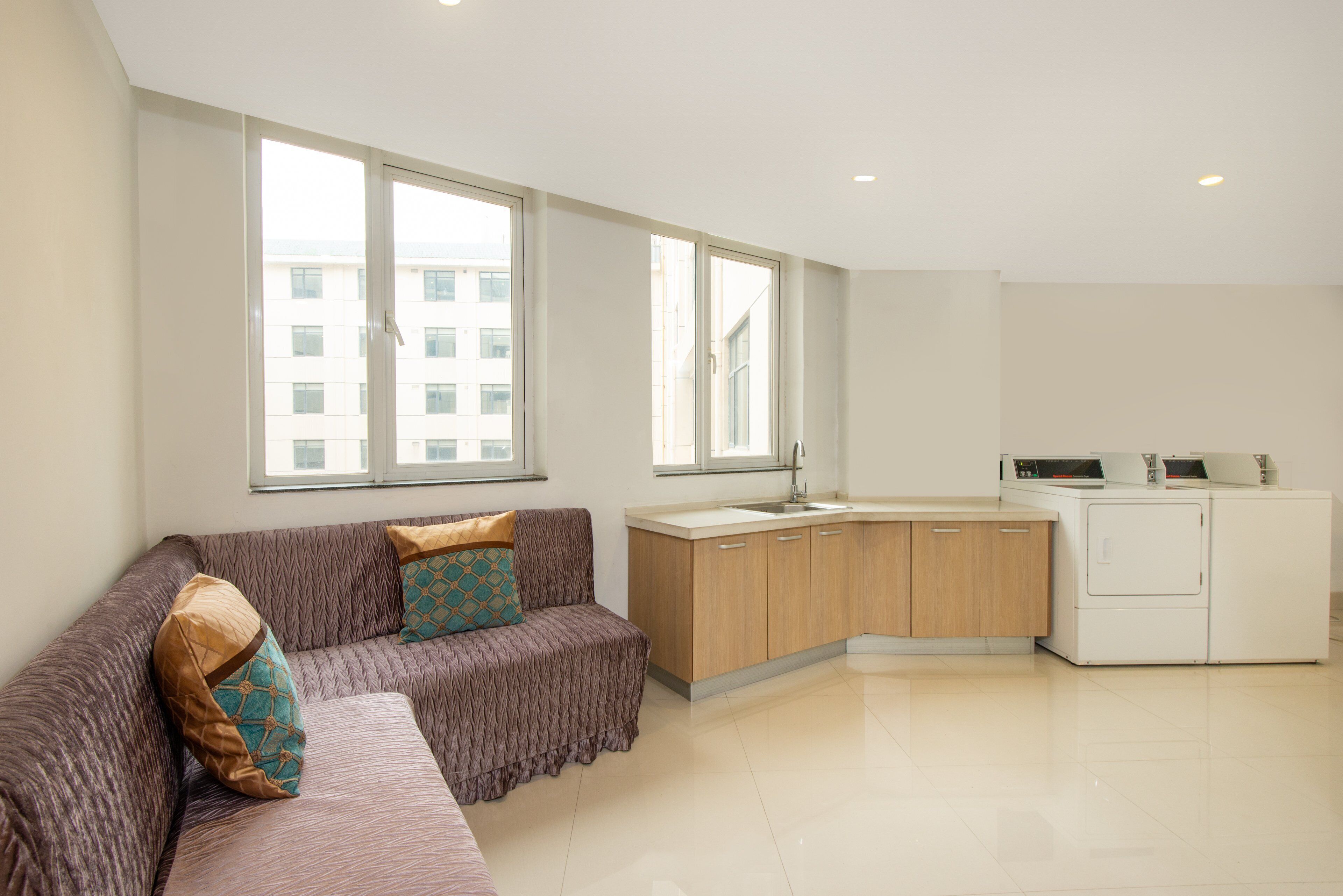 A modern apartment with a sofa, a kitchen area, and large windows.