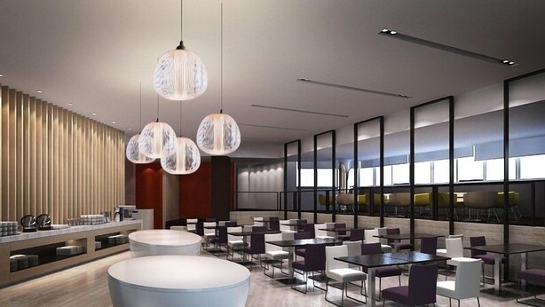 Un espace repas moderne avec des tables et des chaises rondes, des luminaires suspendus et un comptoir de bar avec des tabourets.