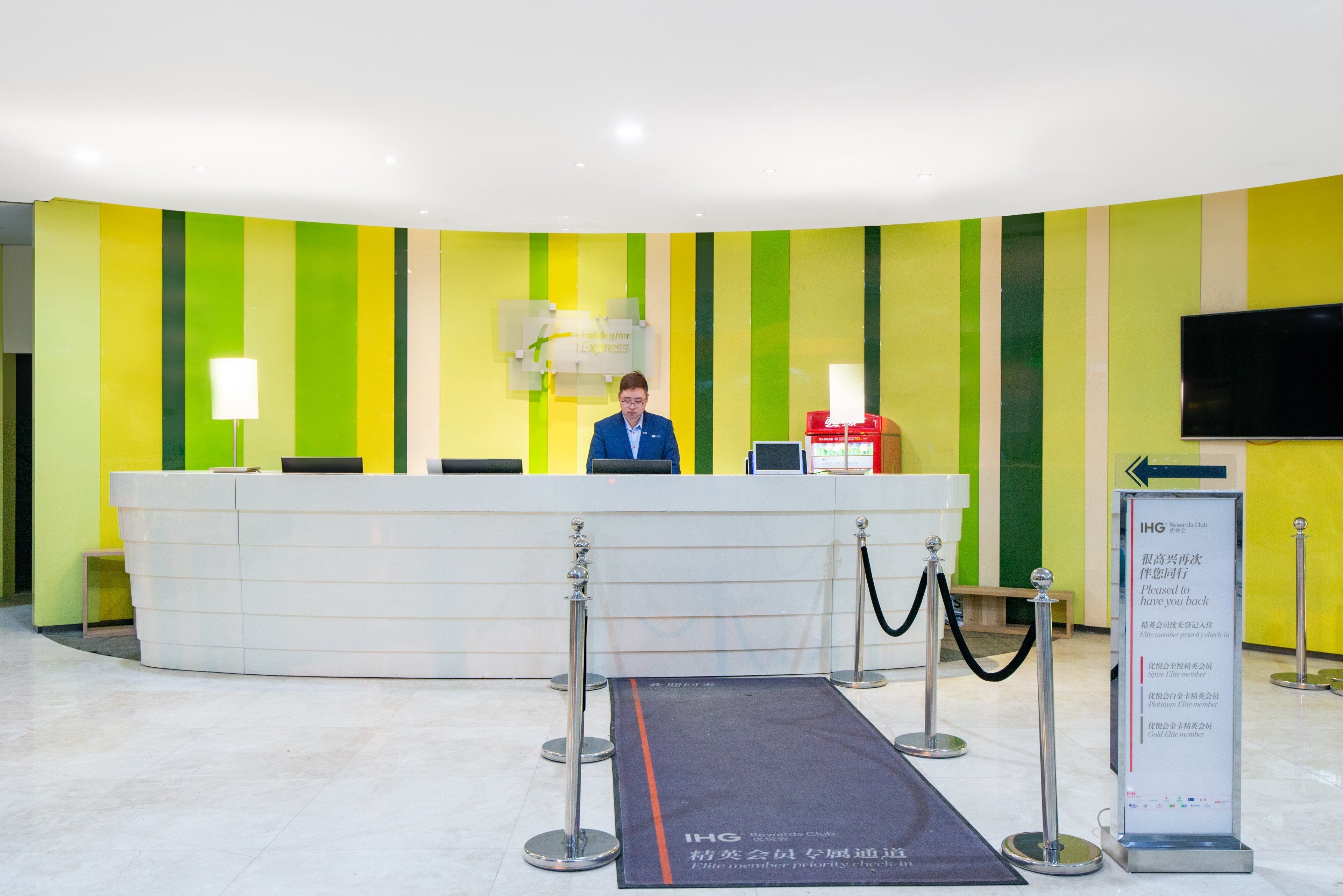 Un mostrador de recepción con diseño moderno, una pantalla digital y una señalizaci ón.