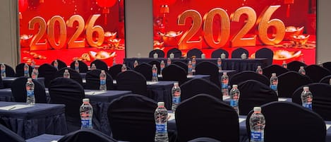 A conference room with tables set up for a meeting, each with a bottle of water and notepads.