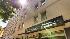 A building with a sign reading "Auto-Parkhotel Hamburg" and a view of trees and a sunlit sky. - Auto-Parkhotel (Hamburg)
