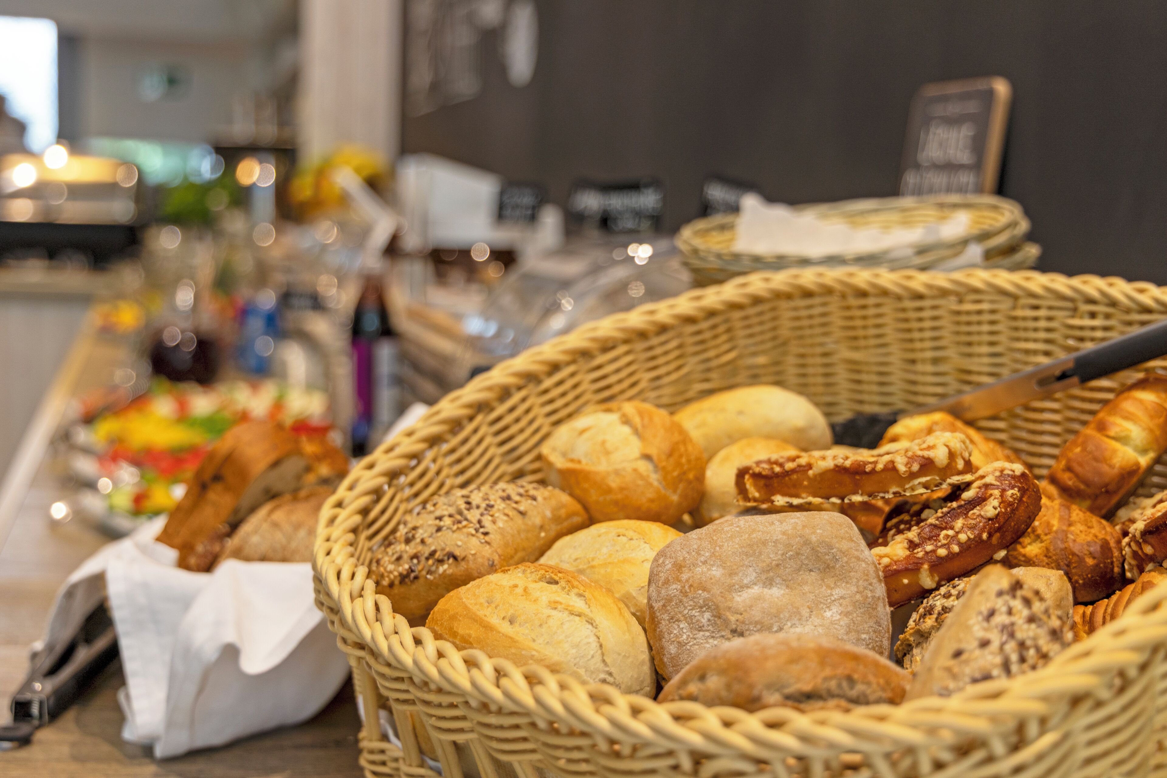 Verschiedene Brotsorten und Gebäck in Weidenkörben auf einem Buffet.
