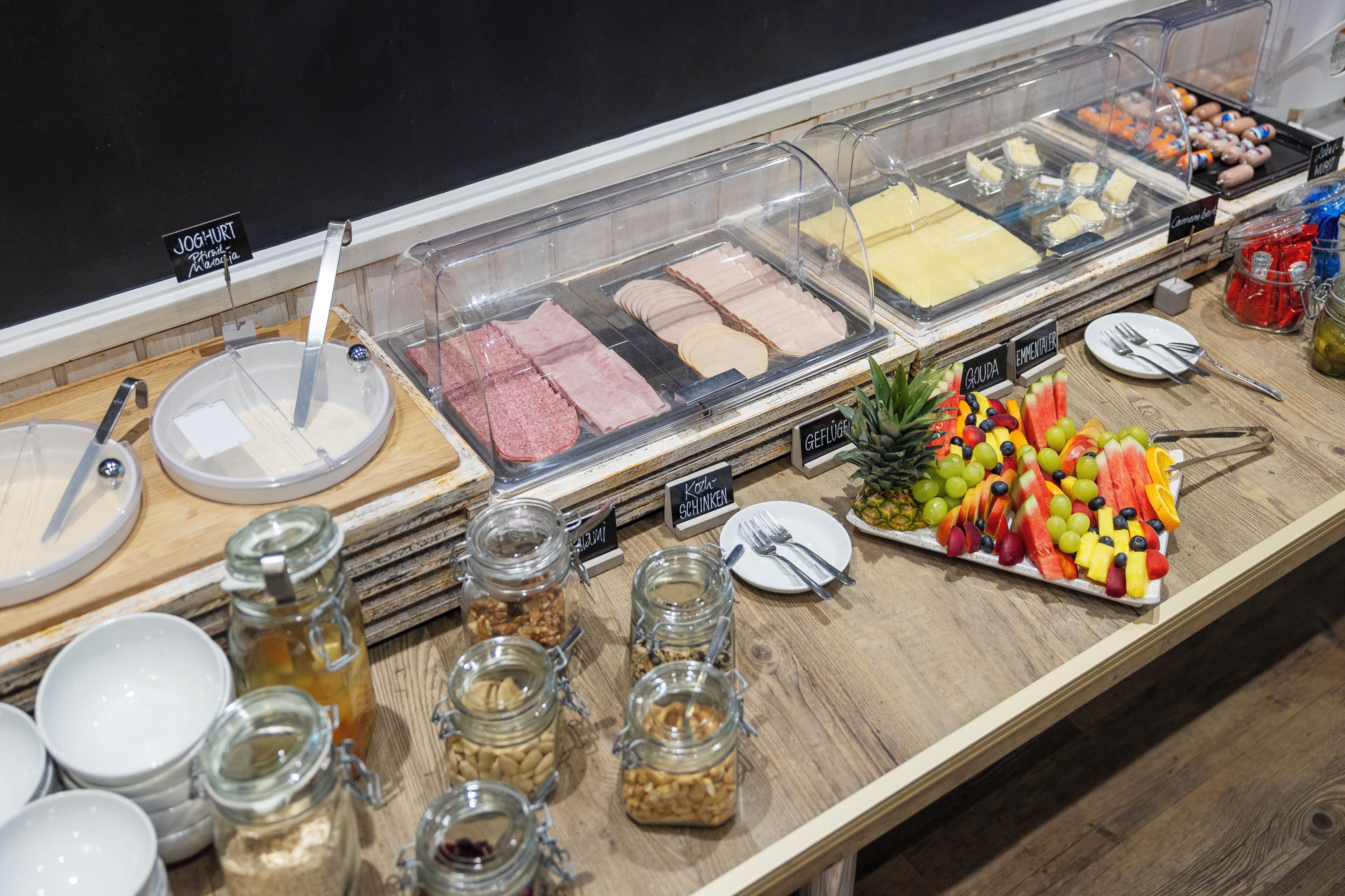 A buffet with various food options including meats, cheeses, and fruits.