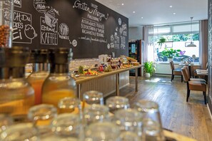 A cafe with a chalkboard wall displaying menu items and a counter with various food and drink options. - Auto-Parkhotel (Hamburg)