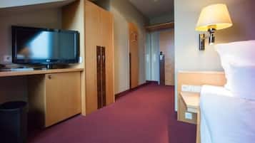 Una habitación de hotel con televisión, armario de madera, cama, lámpara y suelo alfombrado.