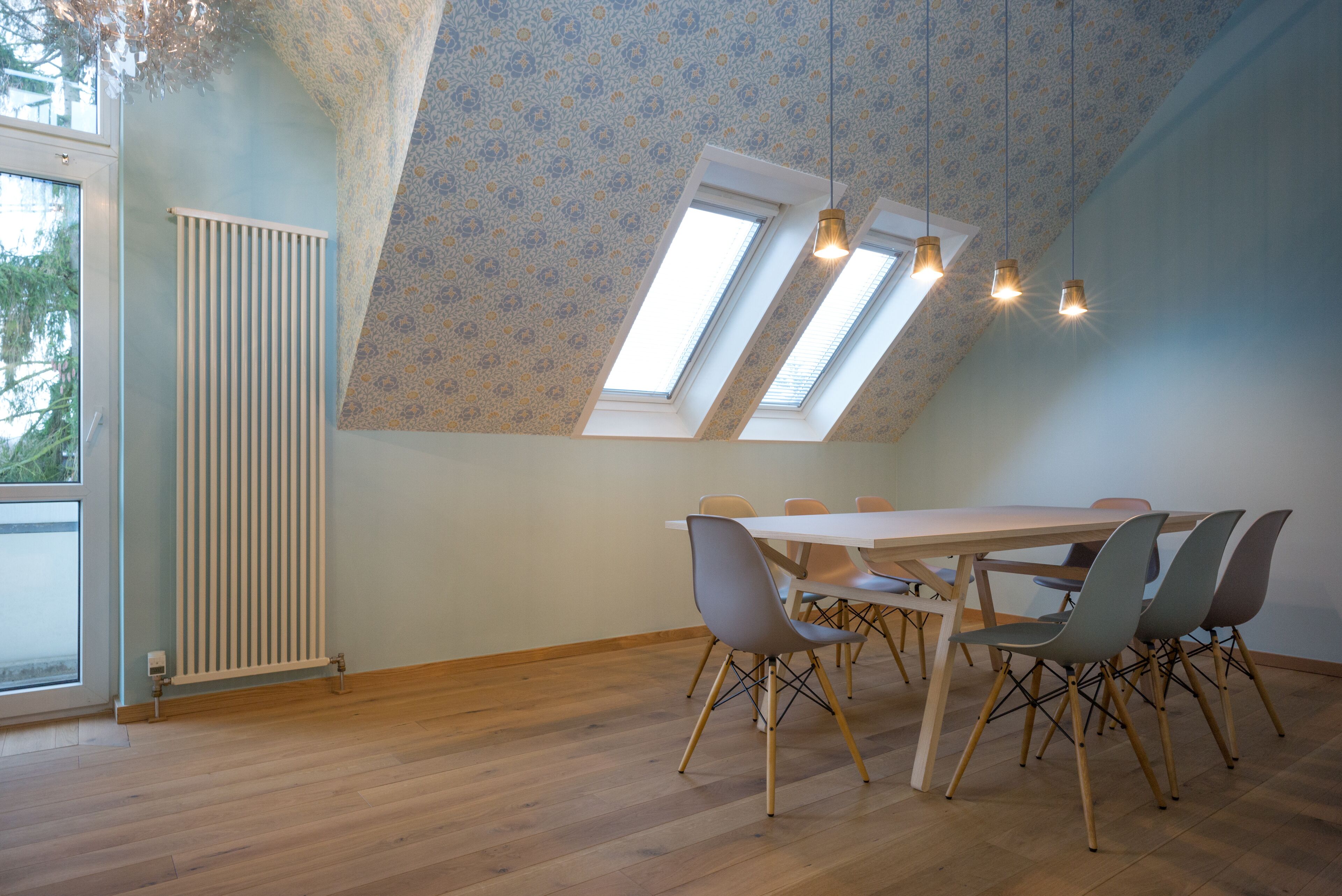 A dining area with a high ceiling, skylights, and a radiator.