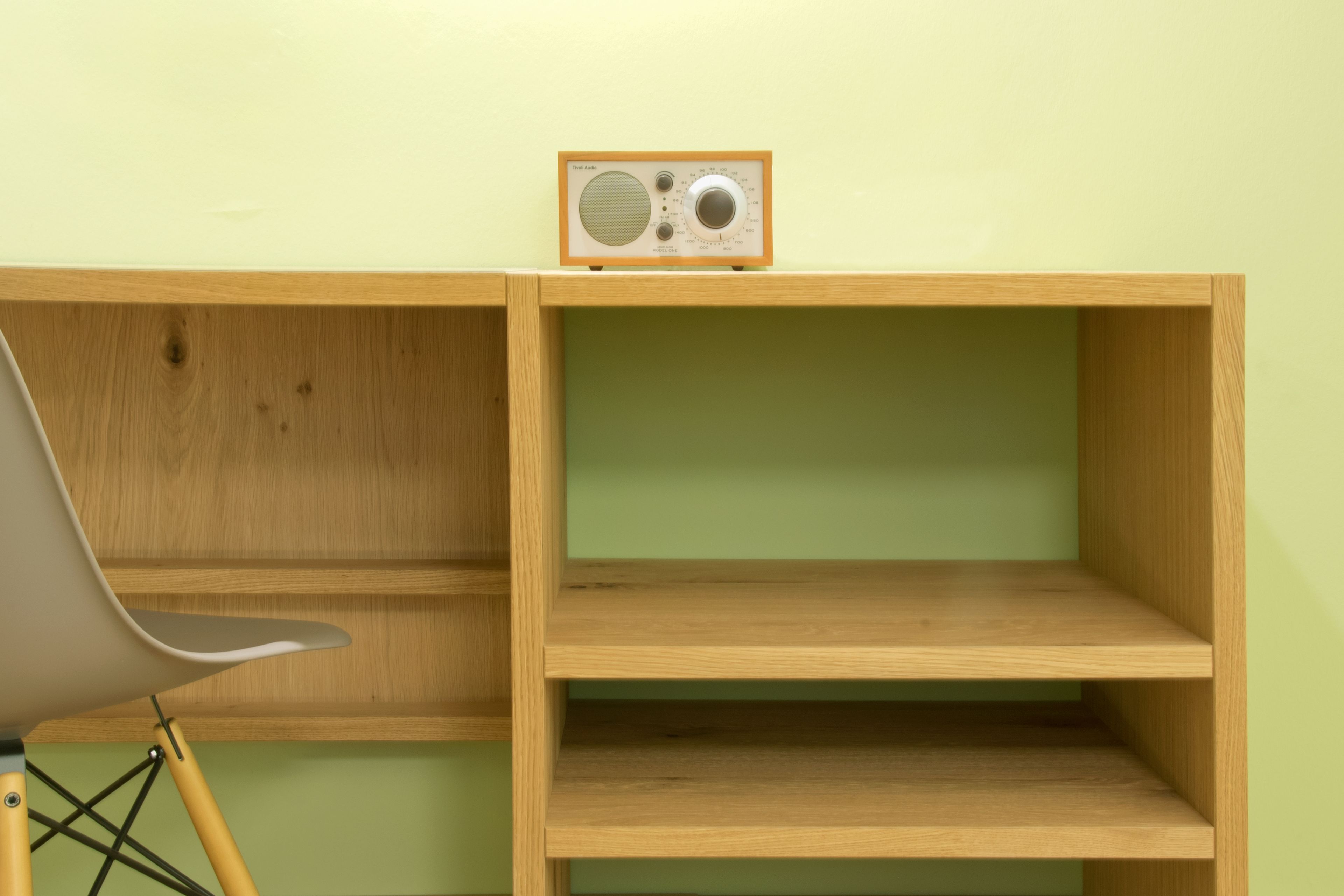 Un escritorio de madera con una radio, una silla y una estantería.