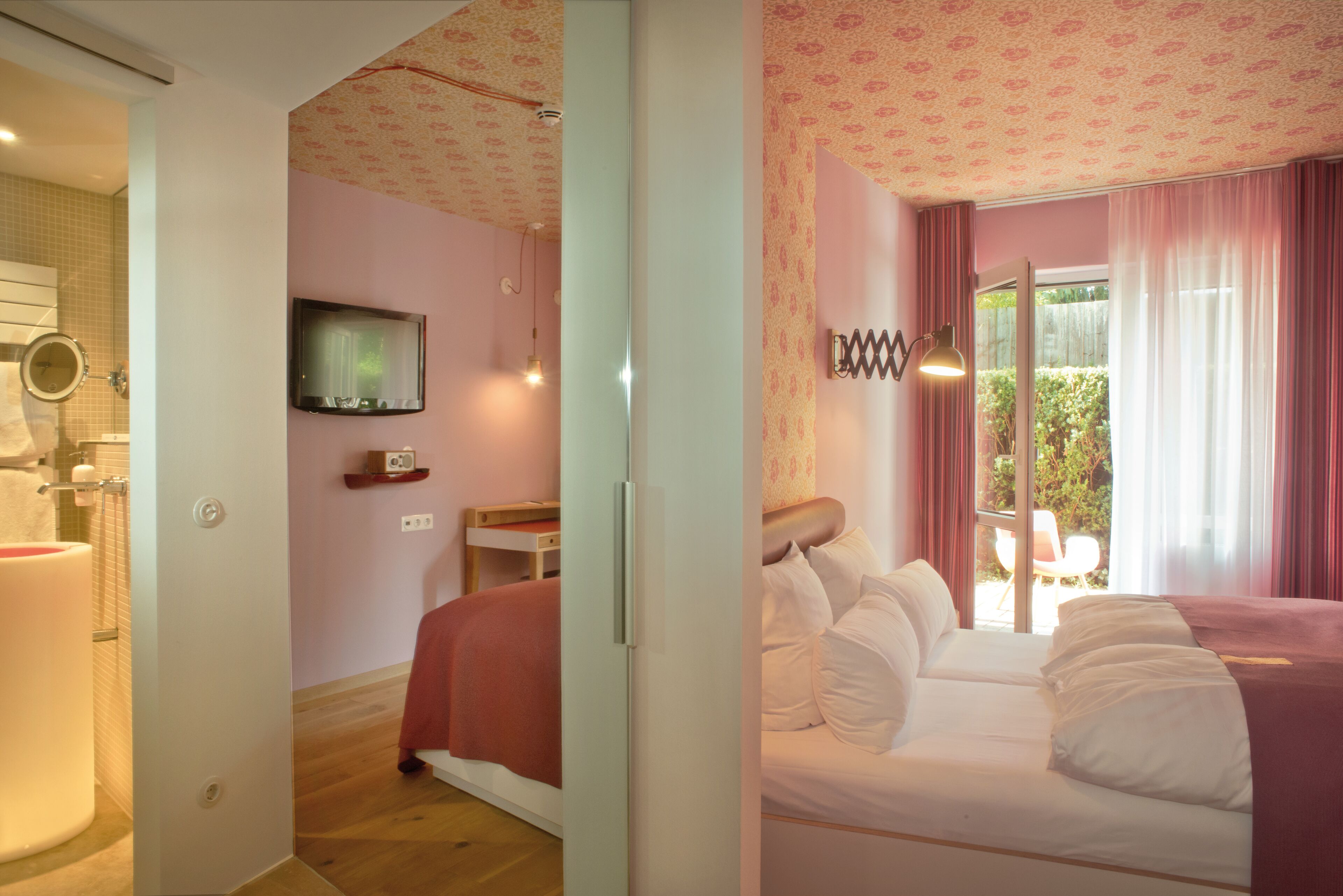 A bedroom with a bed, a television, and a bathroom with a mirror and sink.