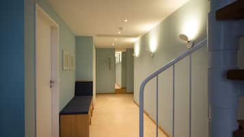 A hallway with a bench, a staircase, and a door.