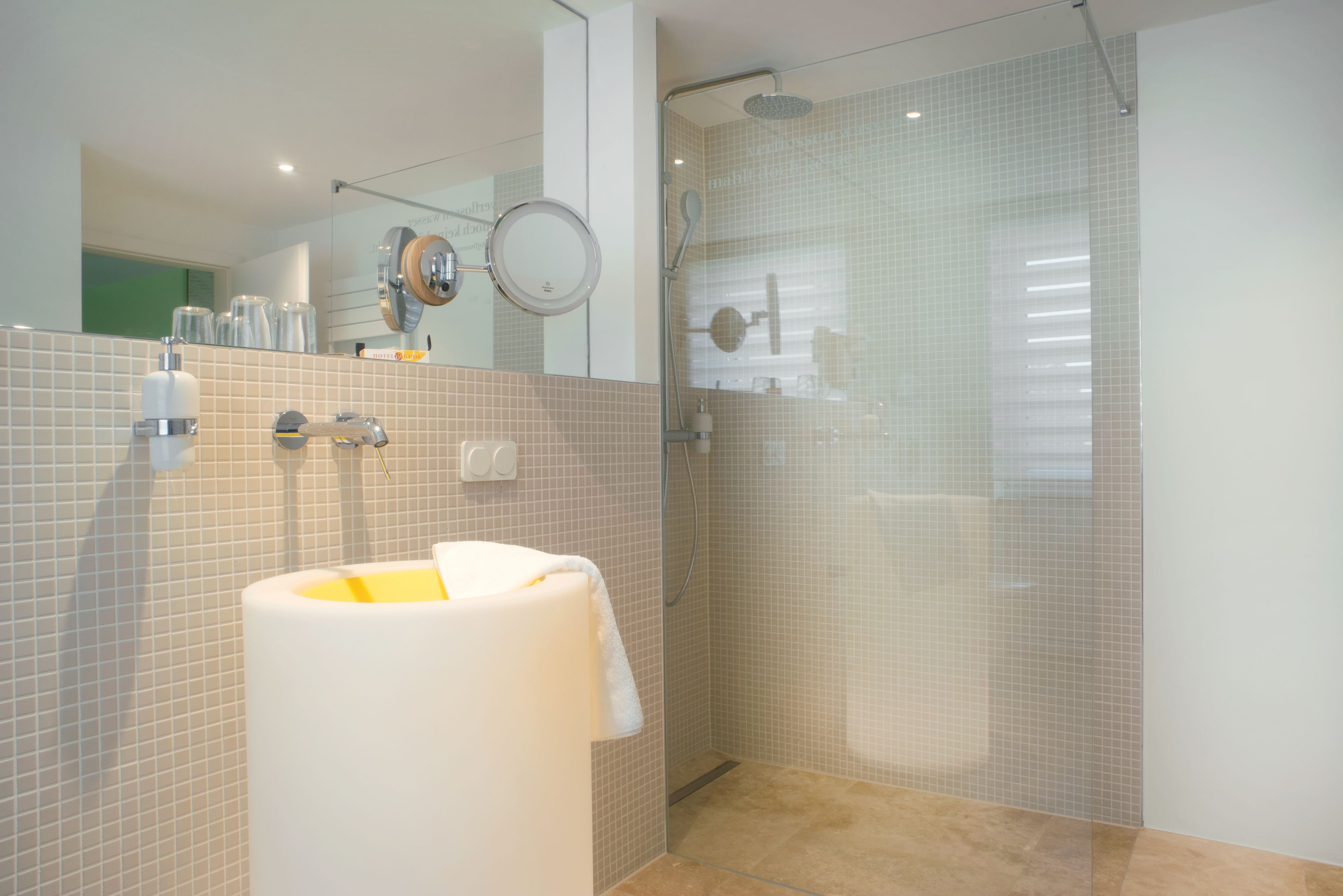 A modern bathroom with a glass-enclosed shower, a white sink, and a mirror.