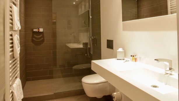 Une salle de bain moderne avec une douche à parois de verre, un lavabo blanc et un grand miroir.