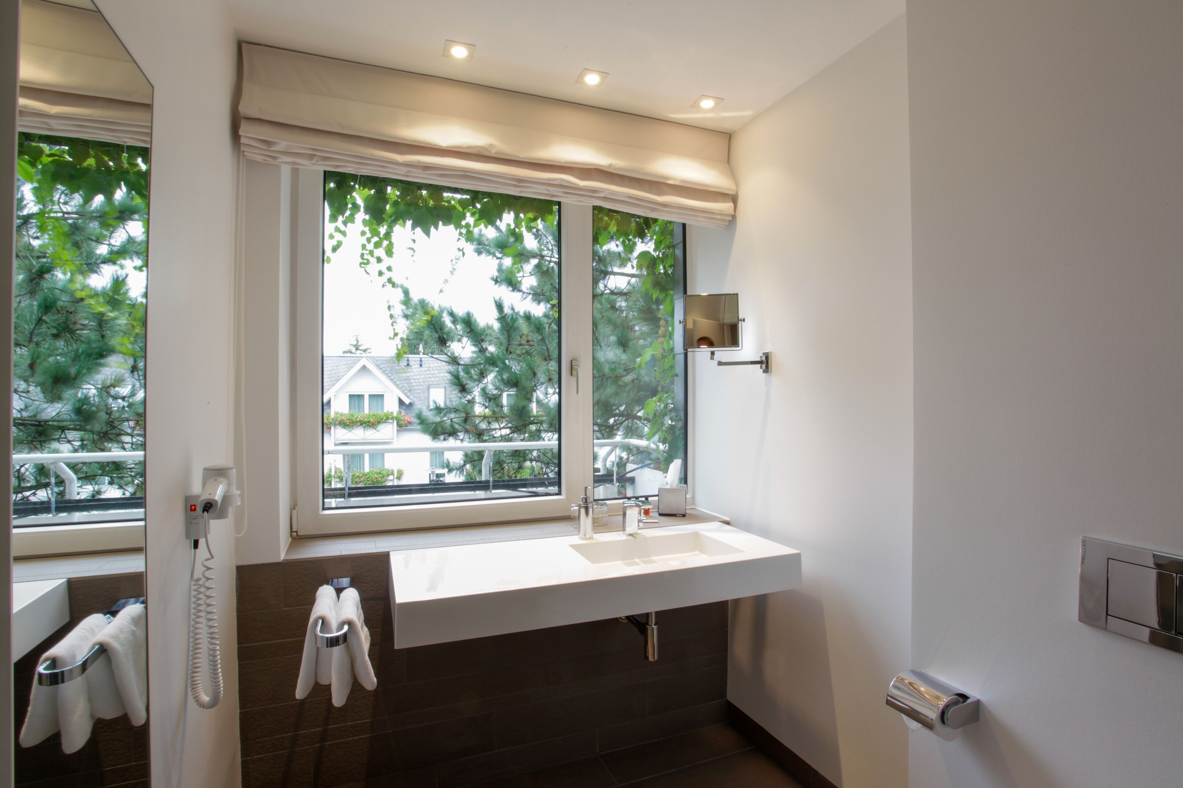 A modern bathroom with a large window, a built-in sink, and a towel rack.