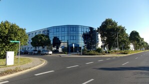 A modern hotel with a curved glass facade, located at an intersection with a clear sky. - Central Hotel Eberswalde (Eberswalde)
