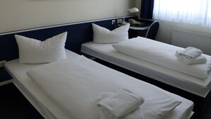 A hotel room with two single beds, each with white linens and pillows, a desk with a lamp, and a window with curtains. - Central Hotel Eberswalde (Eberswalde)