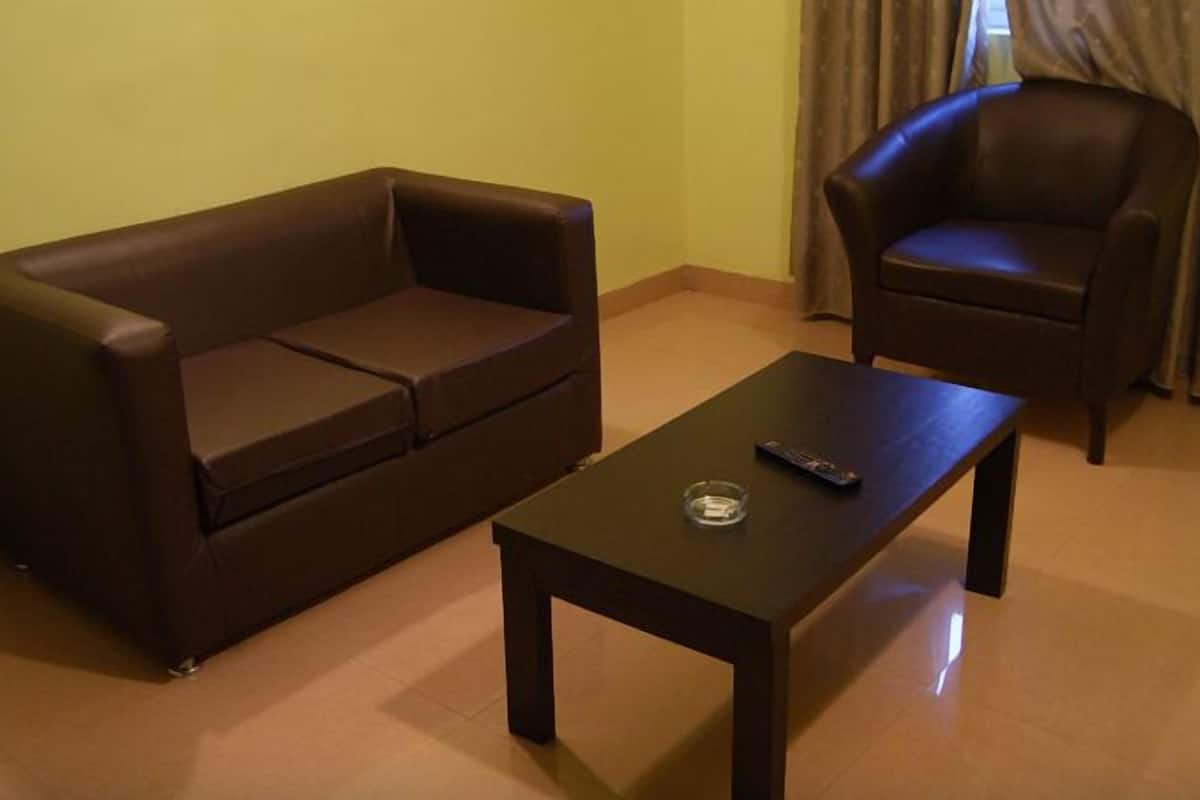 A living room with a brown sofa, a matching armchair, and a small table with a remote control.