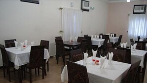 A dining area with multiple tables and chairs, white tablecloths, and neatly arranged napkins. - Hotel Monte Carlo (Enugu)
